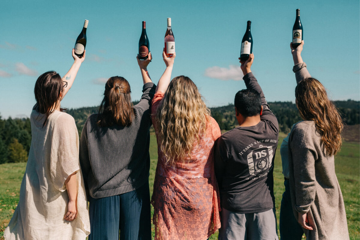 Group of people holding up wine bottles