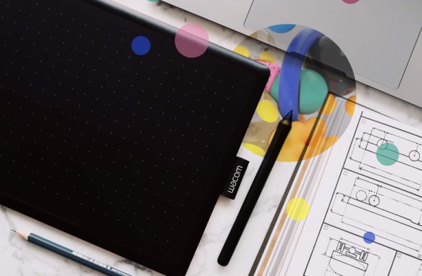 A drawing tablet with pens, pencils, and a laptop