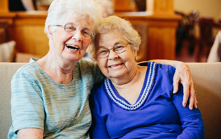 Two older women sitting together on a couch