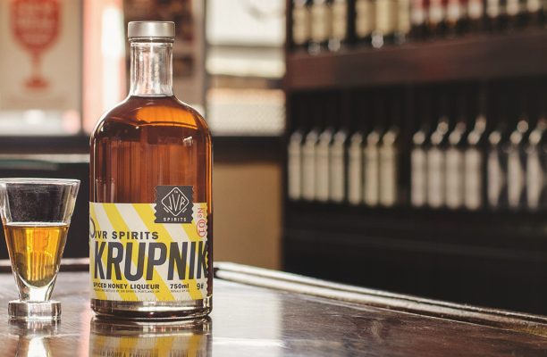 A bottle of Krupnik liqueur with two glasses next to it